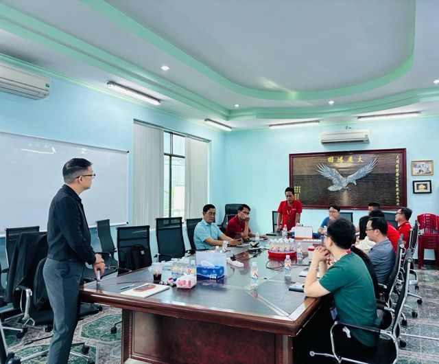 Anh Cường đứng nói chuyện trong phòng họp