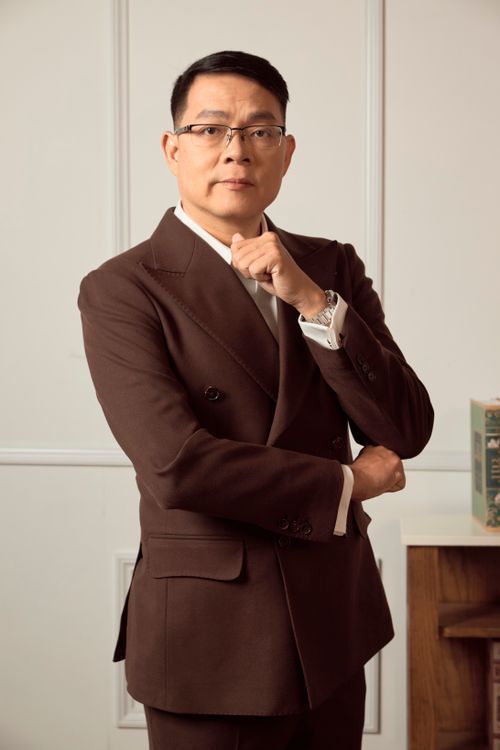 Anh Cường mặc vest nâu, tay chống cằm